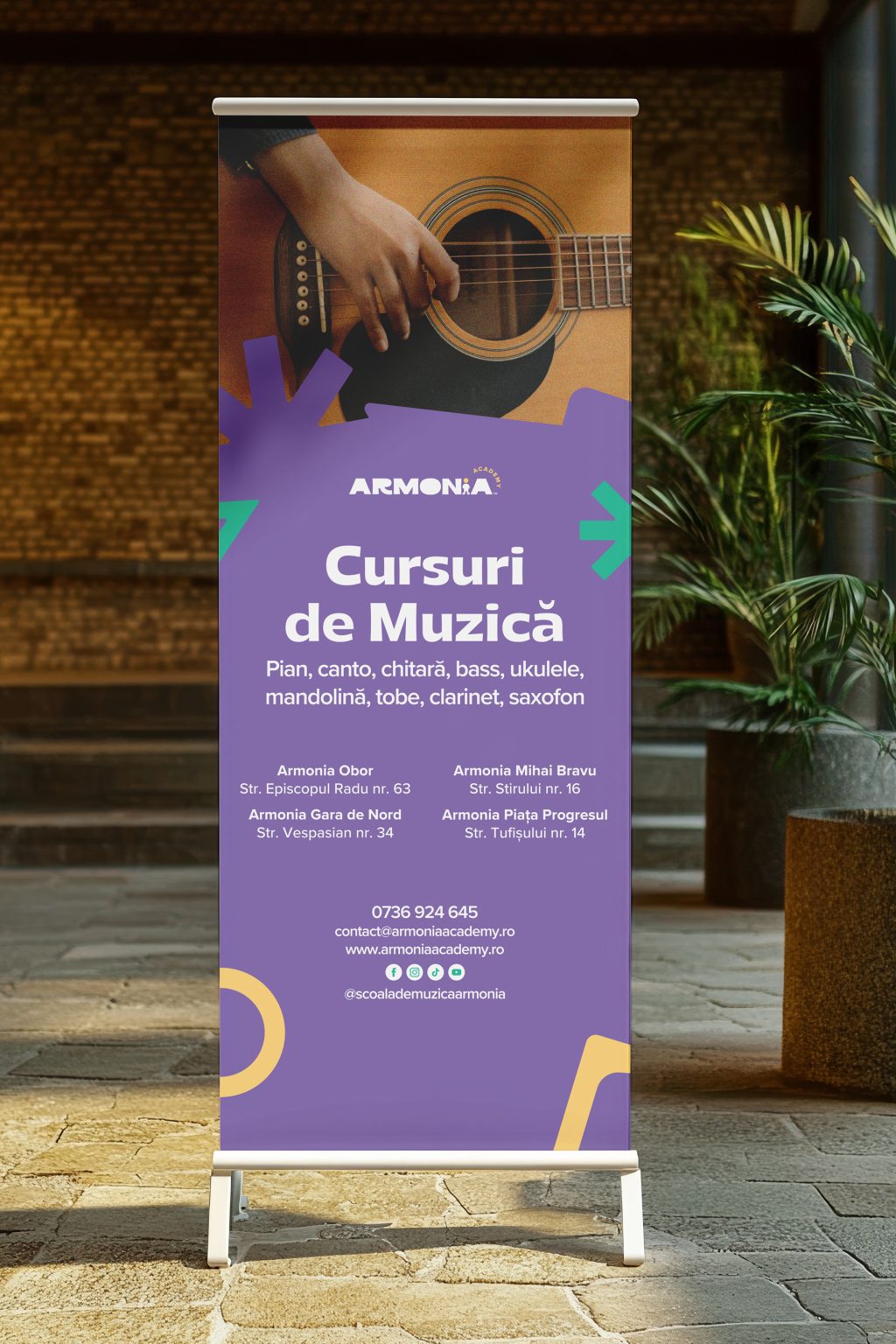 Armonia Academy roll-up banner, “Cursuri de muzică”: a guitar photograph, a purple field with green and yellow shapes, the list of instruments and the school's locations