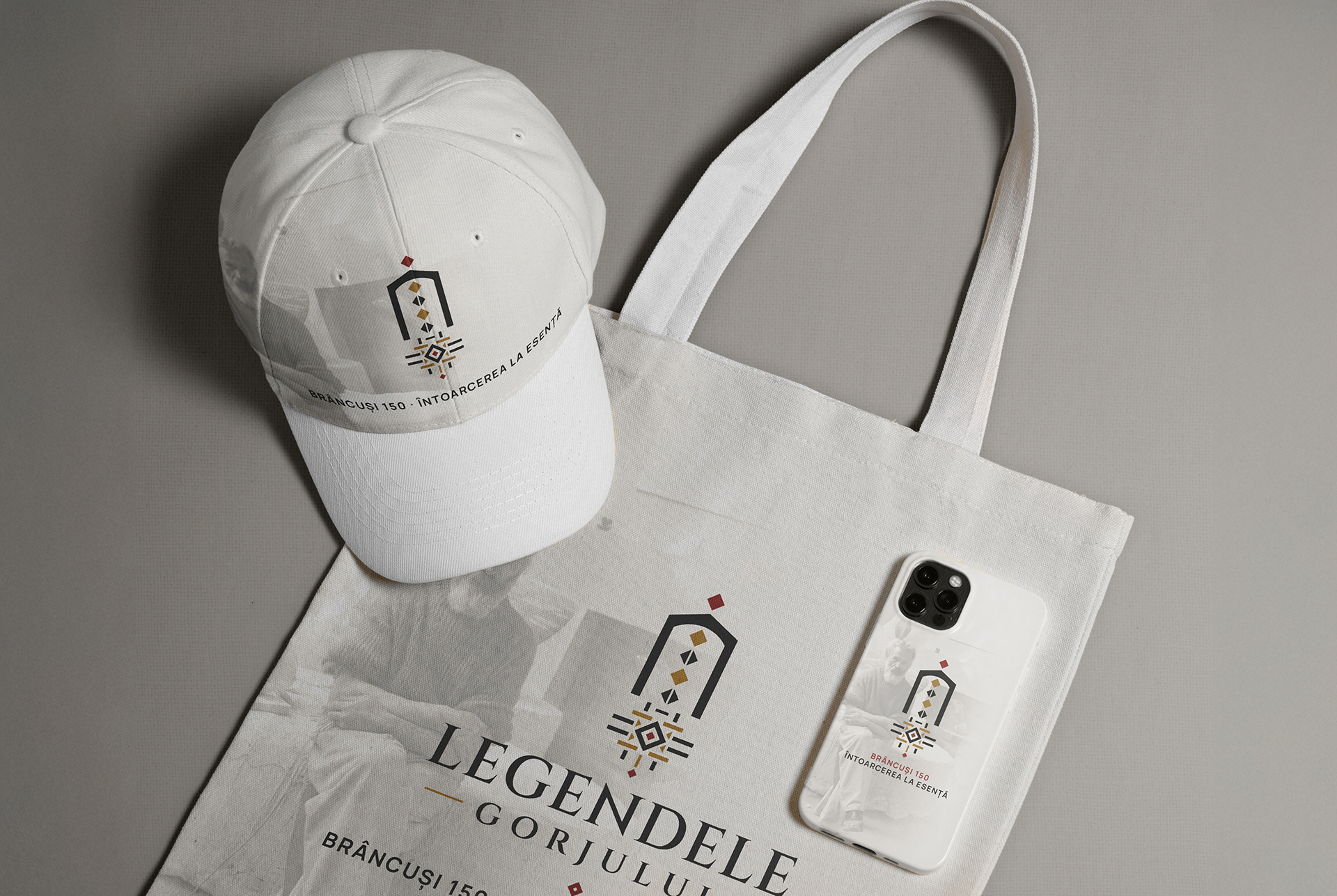 White cap, canvas tote bag and phone case carrying the Legendele Gorjului emblem and the “Brâncuși 150” edition theme