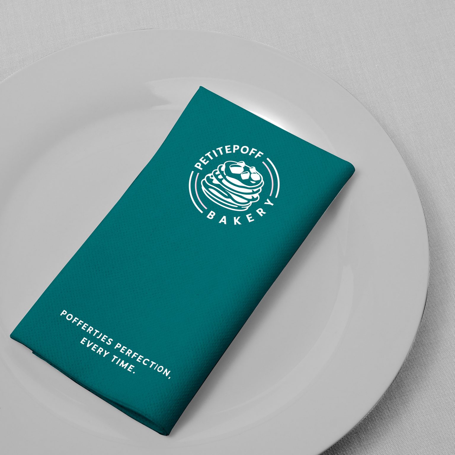 Folded teal napkin on a white plate, with the logo and the line “Poffertjes perfection, every time.”